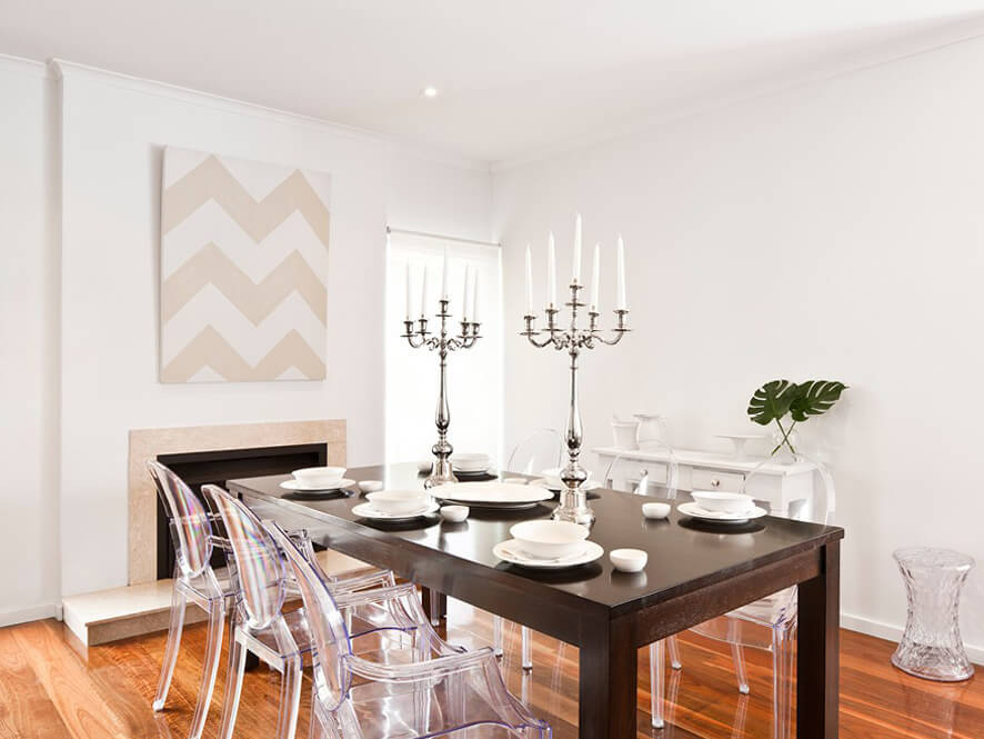 White Modern Dining Room with Timber Floorboards and clear chairs and dark wooden table and candles